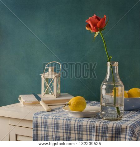 Still life with rose in the bottle and lemons