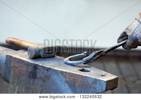 Blacksmith forges a horseshoe for horse close up