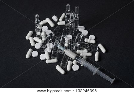 Addiction Topic: Ampoule With Drug And Syringe Tablets Lie On A Dark Background