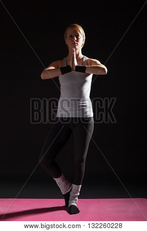 Young woman practicing yoga, Garudasana / Eagle pose