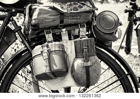 Close up photo of old military bicycle with equipment. Backpack and containers for food and drink. Vintage scene. Black and white photo. Retro transport. Equipment of german soldier in World War II.