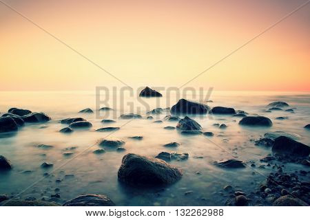 Romantic Morning At Sea. Big Boulders Sticking Out From Smooth Water Level. Pink Horozon With First