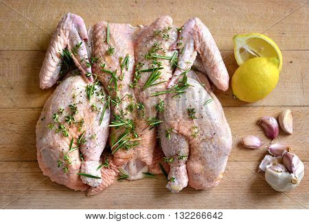 Raw spatchcock chicken with garlic herbs and lemon