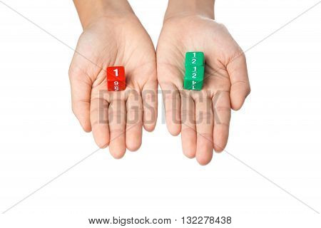 Two hands holding fraction dices one hand with one red dice showing number one the other hand with two green dices showing one half numbers selective focus on dices on white background