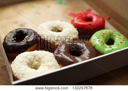 Colorful donuts in box, half-empty box, coconut topping