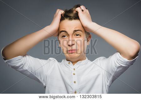 Closeup Portrait of handsome boy with astonished expression while standing against grey background.