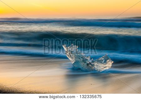 Ice on the beach rolled by waves in the sunrise