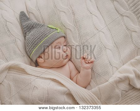 Sleppy little baby in the cap under the blanket