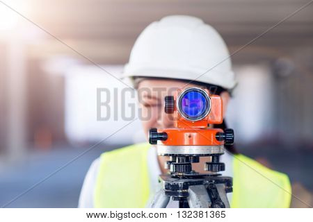 Level usage. Concentrated and busy young woman using a geodetic level standing in a new building