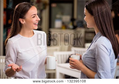 Get a relaxation. Overjoyed delighted smiling women talking and drinking coffee while resting