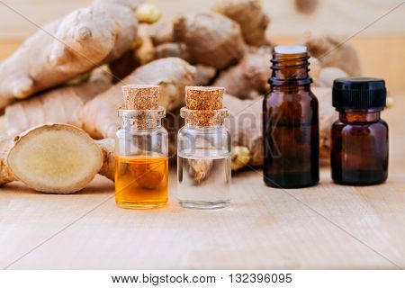 Bottles Of Ginger Oil And Ginger On Wooden Background With Selective Focus.