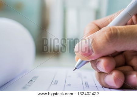 Hand with pen over application form on blure water glass background