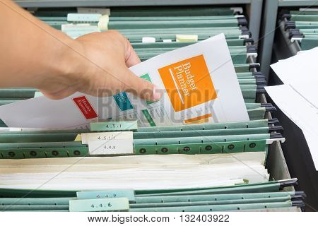 Hand holding report file in filing cabinet