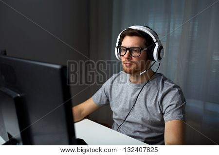 technology, gaming, entertainment, let's play and people concept - young man in headset and glasses with pc computer playing game at home and streaming playthrough or walkthrough video