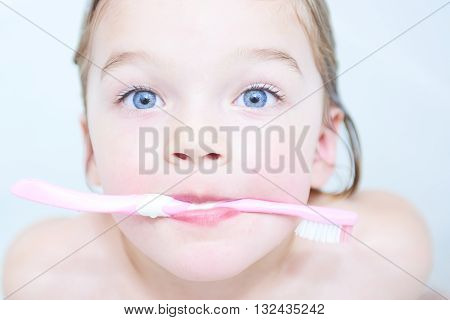 Dental hygiene. Close up of little girl brushing her teeth. Fun in the bath