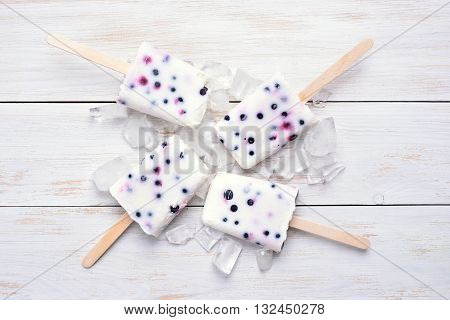 Homemade frozen ice cream popsicles from yogurt and blueberry on wooden bckground top view