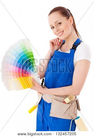 Young woman in  coverall with a color guide and paintbrushes on a white background.