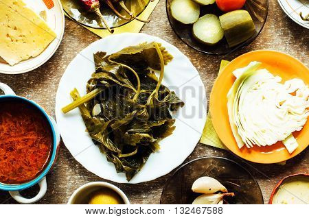 Cucumber marinated bowl with pepper and garlic. Group of fermented veggies on the plate. Overhead view on vegetarian style dinner with vegetable soup pickled cucumbers pickled peppers cabbage.