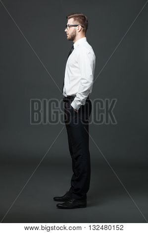 Fullbody Profile View Of Handsome Businessman On Dark Gray Background.