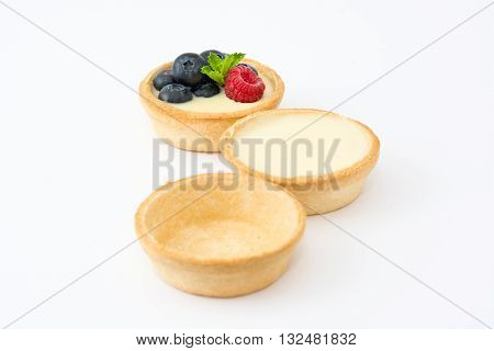 Delicious tartlets with raspberries and blueberries isolated on white background