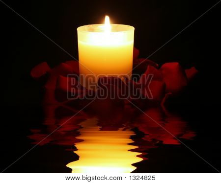 Candela circondato da petali di rosa con riflesso sognante