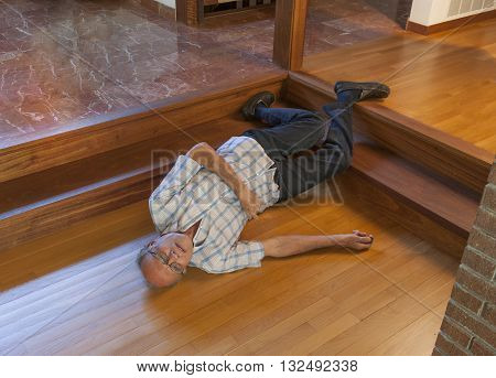 Senior man fell down the stairs and his calling for help with the beeper in his right hand