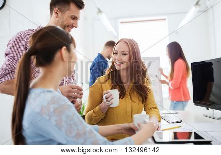 business, startup and people concept - happy creative team or students drinking coffee at office