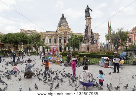 La Paz, Bolivia - October 24, 2015: People feeding pidgeon on Plaza Murillo.