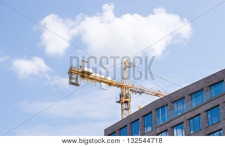 Construction crane and a building house against sky background