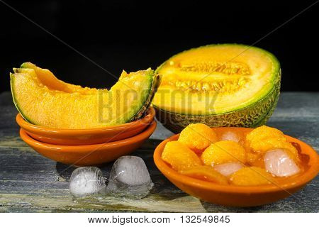 Fresh cantaloupe melon and ice on dark background copy space hot summer concept