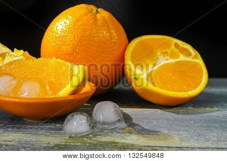 Fresh orange fruits and ice on dark background copy space hot summer concept