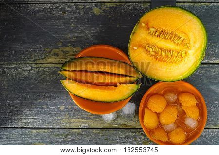 Fresh cantaloupe melon and ice on dark background copy space hot summer concept