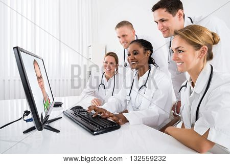 Group Of Doctors Videoconferencing On Computer In Hospital