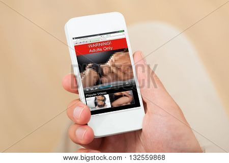 Close-up Of A Person Hand With Adult Movie On Mobile Phone