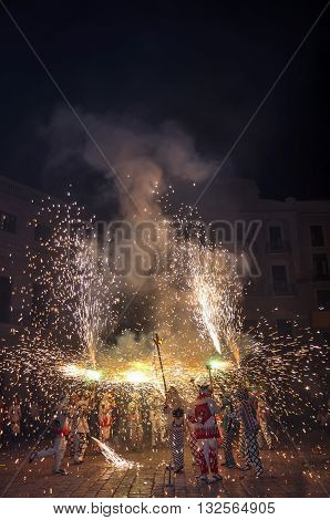Traditional catalan spectacle called Correfocs (fire runs) or Ball de Diables (Devils' Dance). People dressed as devils and dancing with lighting fireworks fixed on devil's pitchforks. Reus Spain. Vertical.