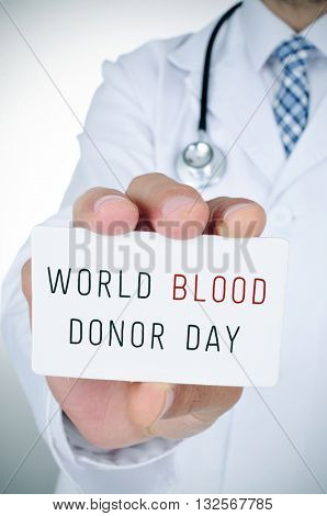 closeup of a young doctor man showing a signboard with the text blood donor day written in it