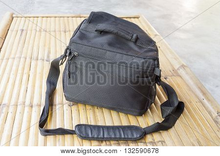 Black camera bag on bamboo floor. select focus front black camera bag.
