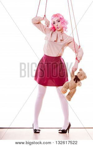 Mental disorder concept. Young woman girl stylized like marionette puppet on string with teddy bear toy isolated on white background