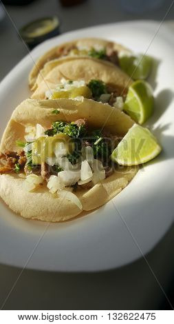 Three delicious carne asada tacos with lime and salsa