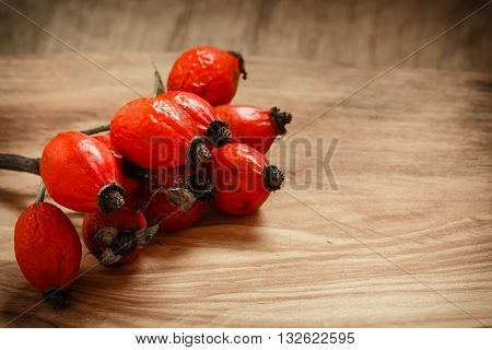 Hawthorn on wooden rustic table background. Rose hips haw fruit of the dog rose.