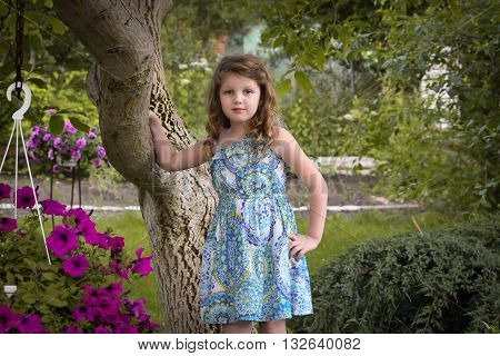 portrait of a little girl on a background of an old tree