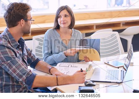 Adult female tutor smiles politely at the male student that she is mentoring to help him reach his full potential