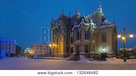 Illuminated House with Chimaeras or Horodecki House. Evening scene. Building and street are powdered with snow.