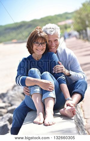 Happy senior couple sitting by the beach