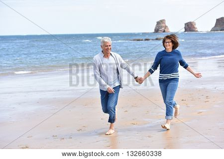 Senior couple running on a sandy beach