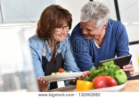 Senior couple in kitchen preparing dish together
