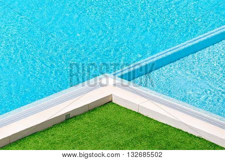 Beautiful luxury Swimming pool resort hotel.Swimming pool and green grass ideal for backgrounds.Hotel swimming pool with sunny reflections close up view.