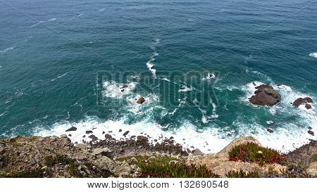 Rocky shore ocean water and foam noisy, hitting the sides.