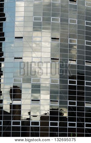 Skyscraper dark mirror glass surface reflecting cloudy sky