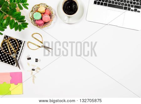 Feminine office desk workplace. Coffee cookies laptop computer and gren plant on white table background. Top view. Flat lay